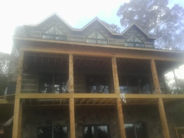 Dormers and porch framing on a large log home under construction — Roof Coating work by our crew in North Sutton
