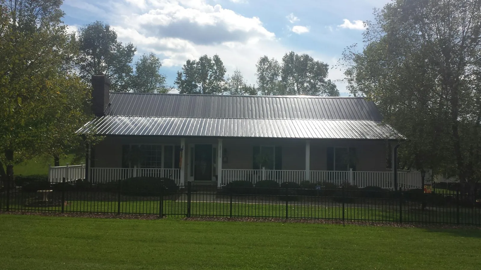 Gray metal roof on a brick ranch with a full width front porch — Gutter Guard Installation work by our crew in North Sutton