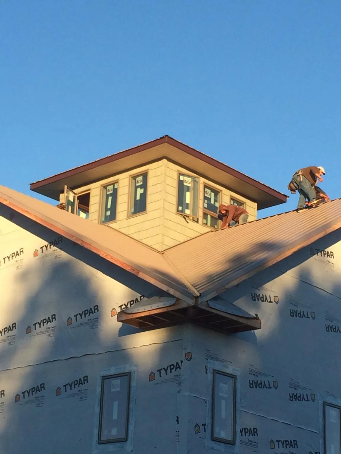 Roofers working around a rooftop cupola on a new metal roof at sunset — Roof Waterproofing in North Sutton by Roofing Brothers